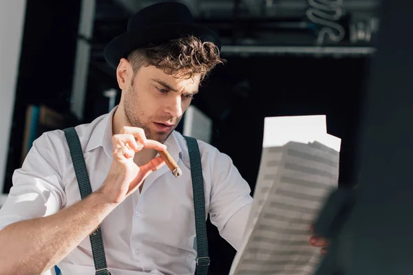 Foco seletivo de músico bonito com charuto, ler notas em folhas de livro de música — Fotografia de Stock