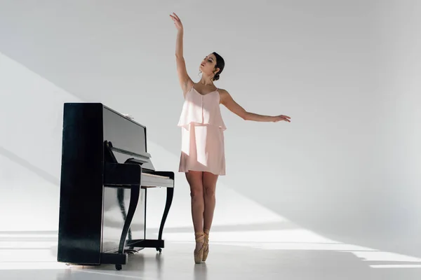 Elegante bailarina bailando cerca de piano negro - foto de stock