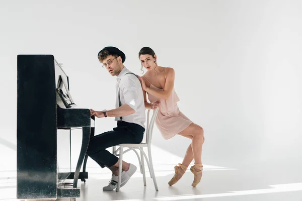 Привлекательная балерина трогает красивого музыканта, играющего на пианино — стоковое фото