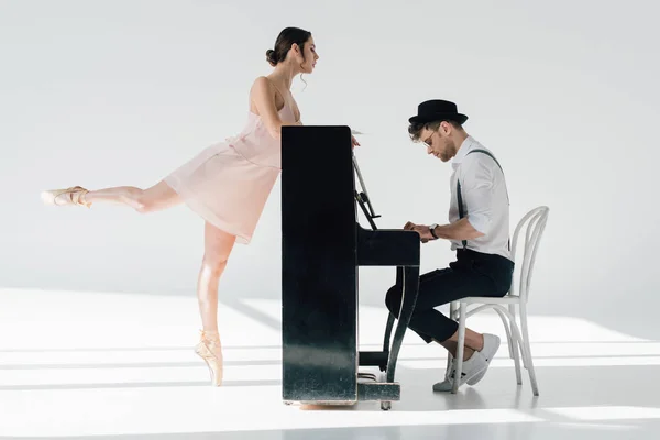 Beau pianiste jouant tandis que belle ballerine dansant près de piano — Photo de stock