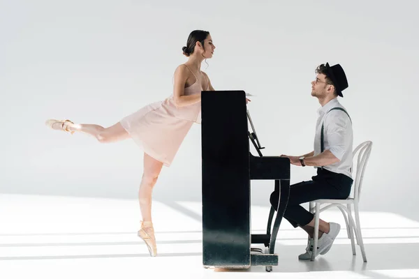 Guapo músico jugando mientras elegante bailarina bailando cerca de piano - foto de stock