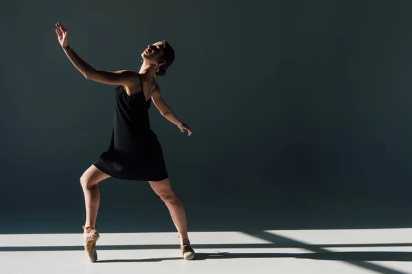 Bela jovem bailarina em vestido preto dançando à luz do sol — Fotografia de Stock