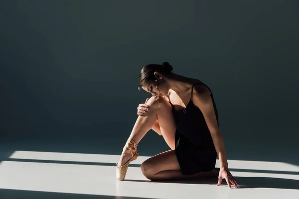 Hermosa bailarina en vestido negro sentado en la luz del sol — Stock Photo