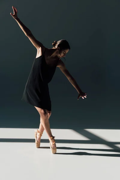 Beautiful young ballerina dancing in black dress and pointe shoes — Stock Photo