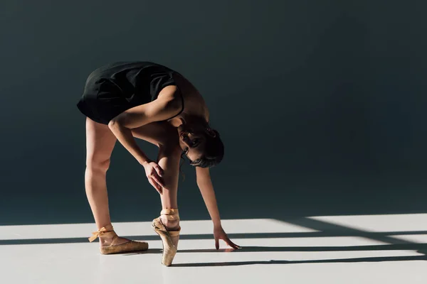 Bela jovem bailarina alongamento em vestido preto — Fotografia de Stock