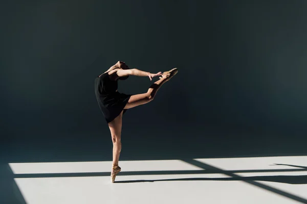 Young ballerina in black dress dancing in sunlight — Stock Photo