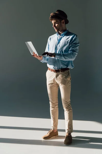Handsome man using laptop while standing in sunlight — Stock Photo