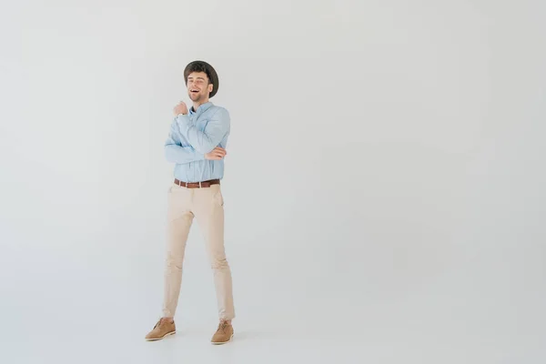 Handsome smiling man in blue shirt and beige jeans isolated on grey — Stock Photo