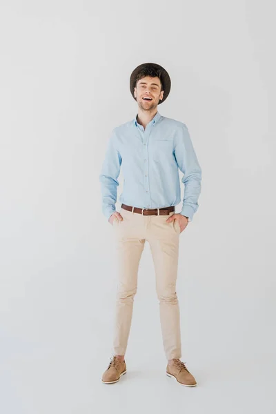 Hombre alegre guapo en camisa azul y pantalones vaqueros beige aislados en gris - foto de stock