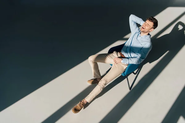 Uomo sorridente che riposa in poltrona alla luce del sole — Foto stock