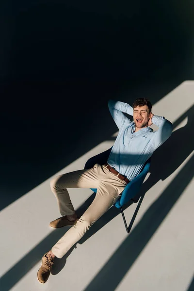 Joyeux bel homme reposant dans un fauteuil à la lumière du soleil — Photo de stock