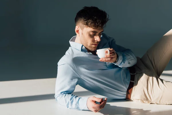 Schöner Mann, der Kaffee trinkt, während er im Sonnenlicht ruht — Stockfoto