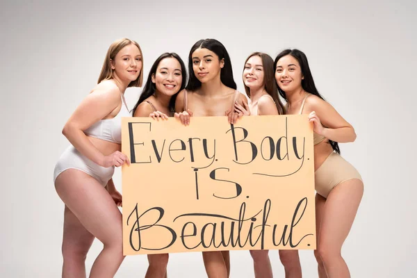 Cinco sorridentes meninas multiétnicas segurando cartaz com 