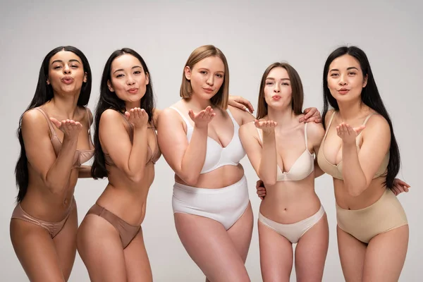 Cinco chicas muy multiculturales en lencería enviando besos aéreos aislados en gris, concepto de positividad corporal - foto de stock