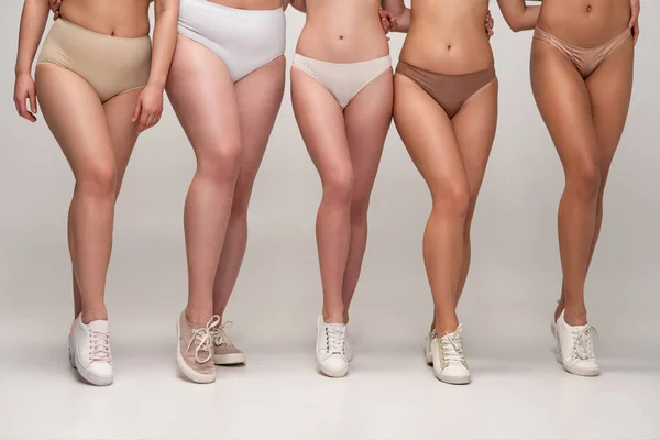 Обрезанное представление о пяти мультикультурных женщинах в нижнем белье и кроссовках, концепция положительной реакции на тело — стоковое фото