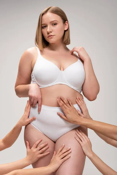 Abgeschnittene Ansicht weiblicher Hände, die ein ziemlich übergewichtiges Mädchen berühren, isoliert auf grauem, körperpositivem Konzept — Stockfoto