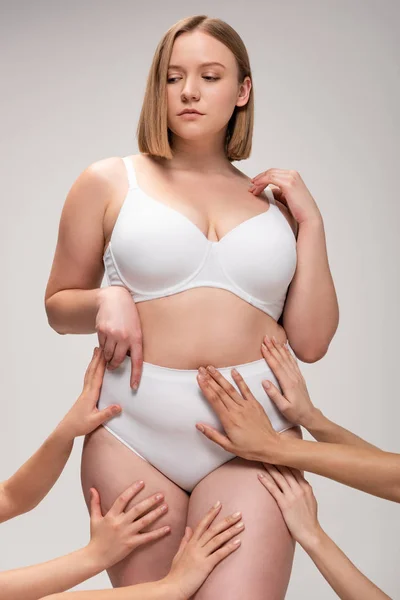 Abgeschnittene Ansicht weiblicher Hände, die ein ziemlich übergewichtiges Mädchen berühren, isoliert auf grauem, körperpositivem Konzept — Stockfoto
