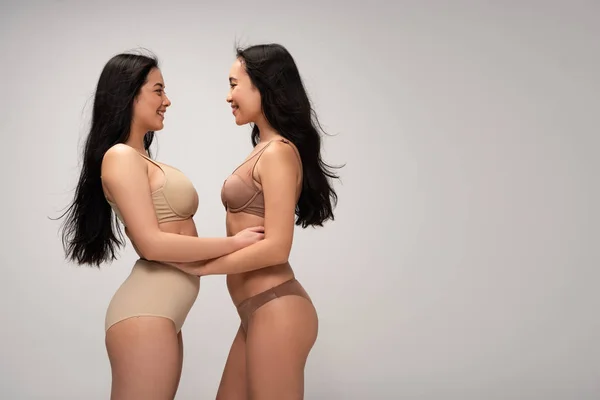 Two pretty multiethnic young women in underwear looking at each other isolated on grey, body positivity concept — Stock Photo