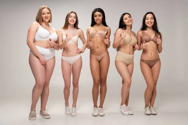Пять довольно мультикультурных молодых женщин в нижнем белье показывая большие пальцы вверх, концепция положительного тела — стоковое фото