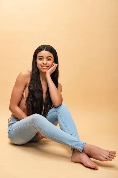 Belle afro-américaine fille assise avec les jambes croisées et regardant la caméra — Photo de stock