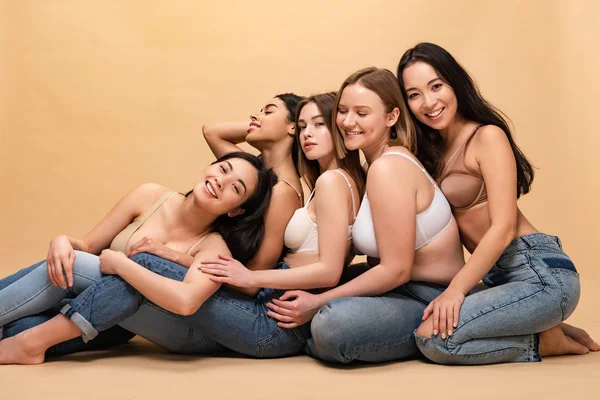 Cinco mulheres multiculturais sorridentes sentadas juntas e apoiadas umas nas outras, conceito de positividade corporal — Fotografia de Stock