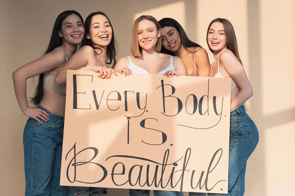 Five happy multicultural girls holding placard with 