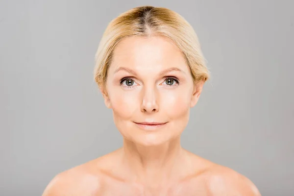 Attractive and blonde mature woman looking at camera isolated on grey — Stock Photo