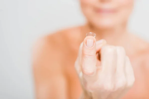 Foco seletivo da lente de contato segurando por mulher madura isolada em cinza — Fotografia de Stock