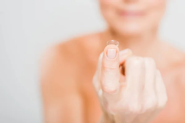 Selective focus of contact lens holding by mature woman isolated on grey — Stock Photo