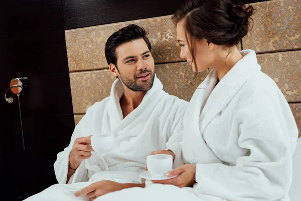 Bel homme regardant la femme attrayante en peignoir avec tasse de café — Photo de stock