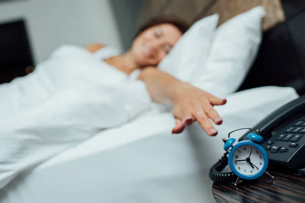 Enfoque selectivo de reloj despertador azul retro cerca de la mujer en la cama - foto de stock