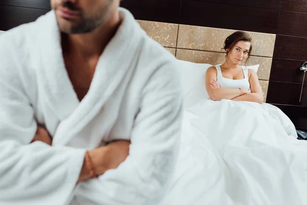 Enfoque selectivo de la atractiva mujer sentada con los brazos cruzados y mirando al novio después de la pelea - foto de stock