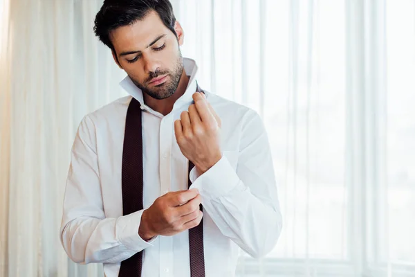 Handsome bearded man touching shirt while standing in hotel — Stock Photo