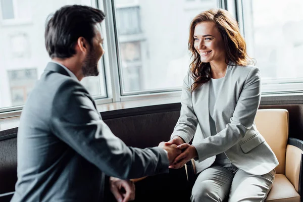 Enfoque selectivo de la alegre empresaria estrechando la mano con el hombre de negocios - foto de stock