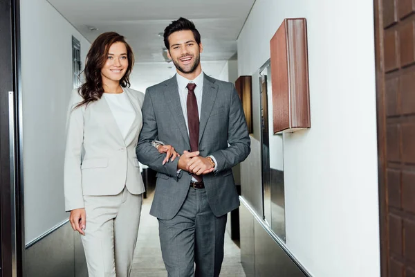 Happy businessman and businesswoman in formal wear walking hotel corridor — Stock Photo