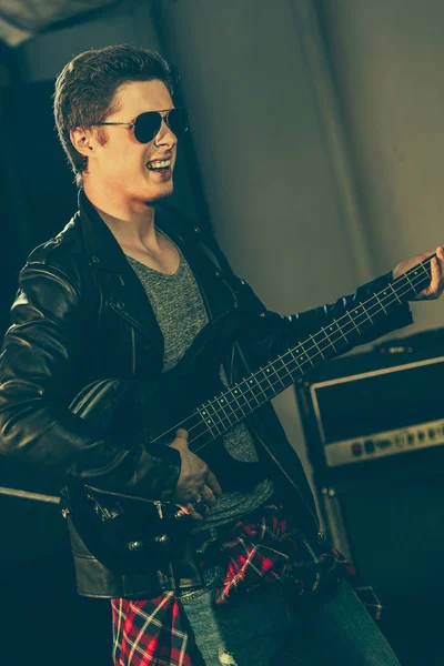 Handsome guitarist in sunglasses performing on stage — Stock Photo