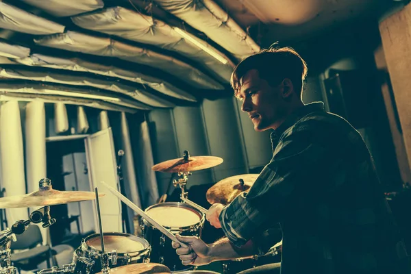 Good-looking musician holding drum sticks and playing drums — Stock Photo