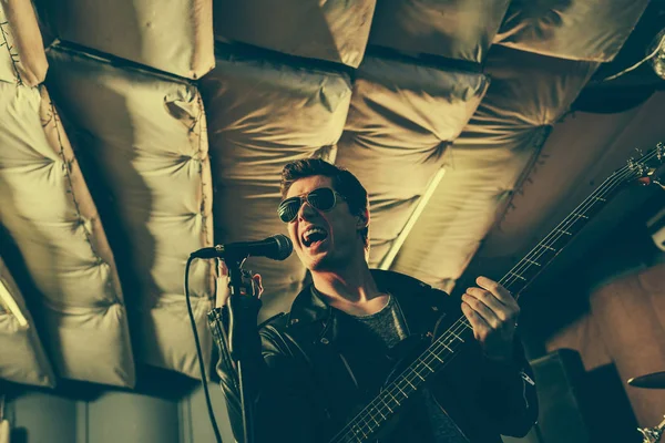 Guitariste chantant une chanson au microphone tout en tenant de la guitare électrique — Photo de stock