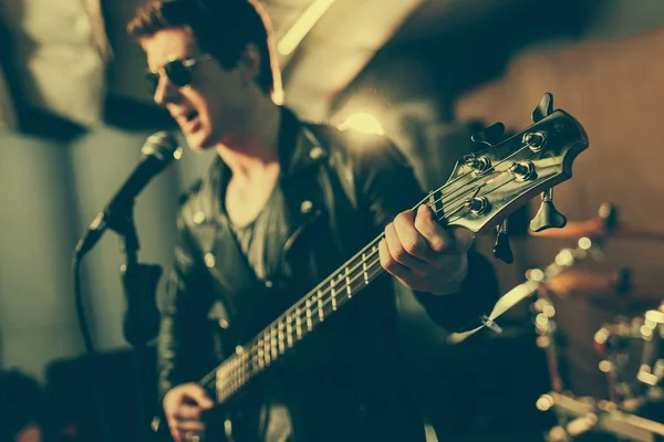 Selective focus of electic guitar in hands of guitarist singing song in microphone — Stock Photo