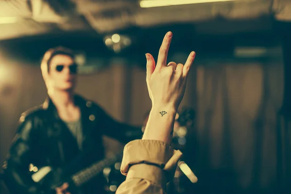 Selective focus of woman showing rock sign near musician — Stock Photo