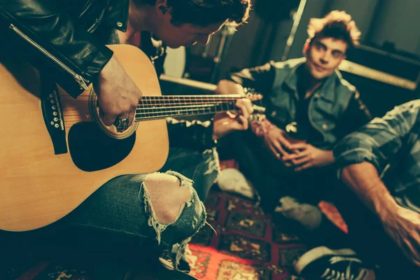 Enfoque selectivo de músico tocando la guitarra acústica cerca de amigos - foto de stock