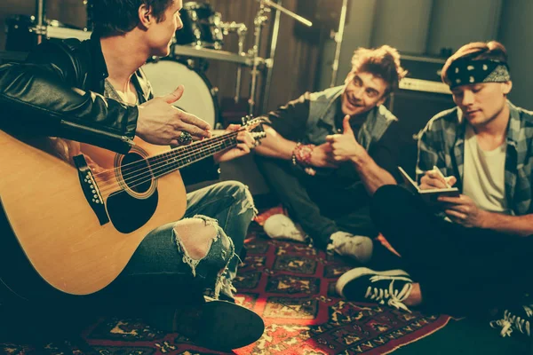 Selective focus of musician holding acoustic guitar near cheerful friends — Stock Photo