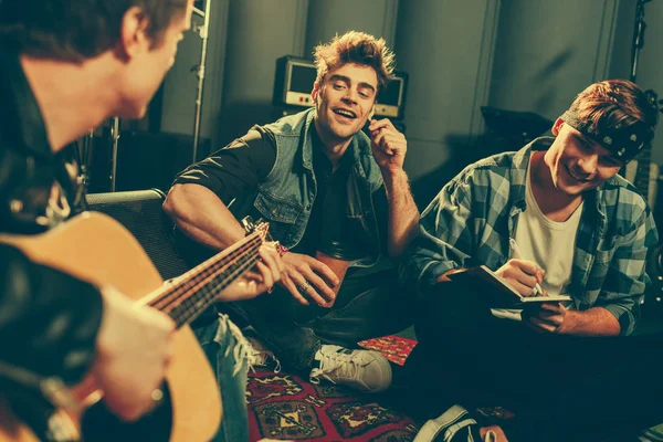 Foyer sélectif d'amis joyeux regardant musicien jouer de la guitare acoustique — Photo de stock