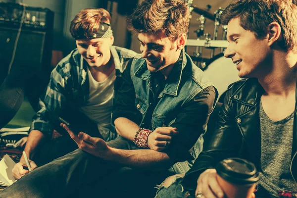 Selective focus of man holding paper cup near friends looking at smartphone — Stock Photo