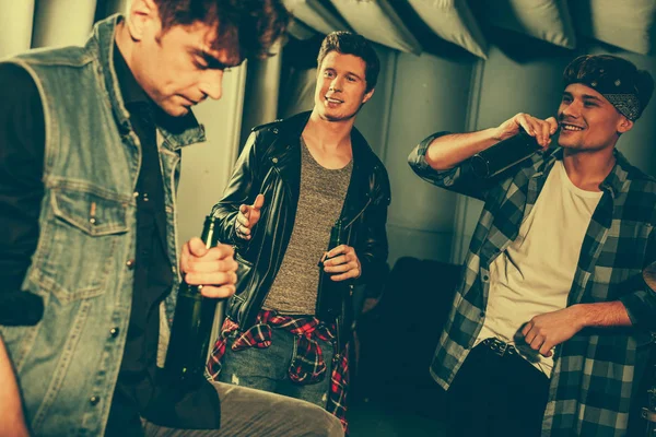 Selective focus of handsome men holding bottles with beer while looking at friend — Stock Photo