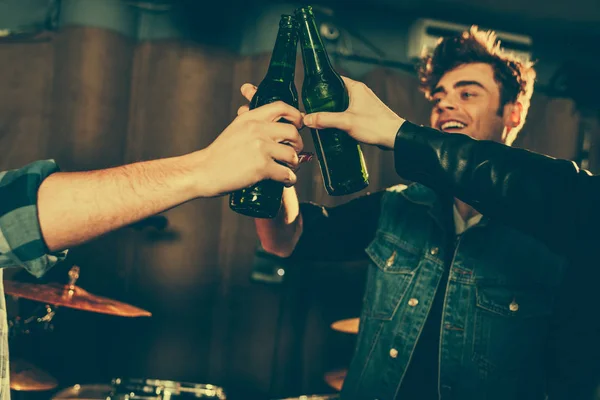 Cropped view of men clinking bottles near cheerful friend — Stock Photo