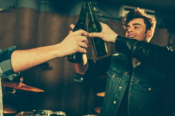 Recortado vista de los hombres tintineo botellas cerca alegre amigo — Stock Photo