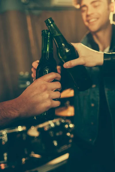 Vista recortada de los hombres tintineo botellas con cerveza - foto de stock