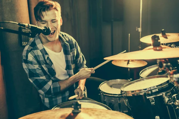 Selective focus of handsome drummer singing in microphone while playing drums — Stock Photo