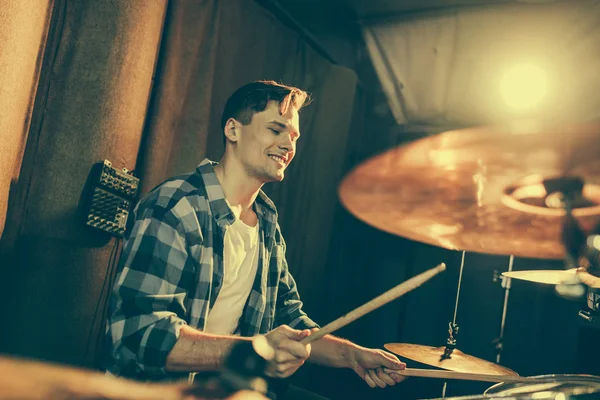 Enfoque selectivo del guapo baterista sosteniendo palos de tambor y tocando la batería - foto de stock